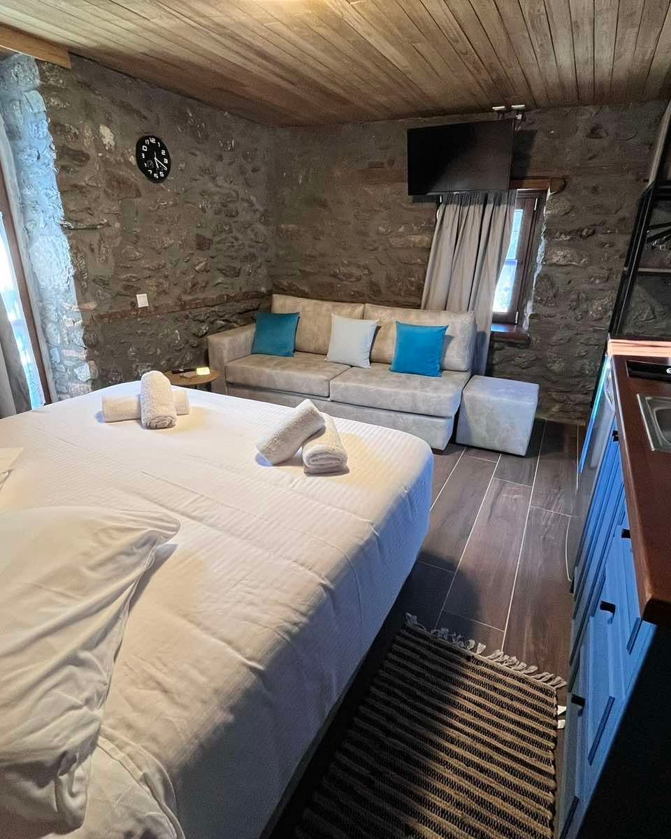 Home 1, white linen and a kitchenette beside a stone wall.