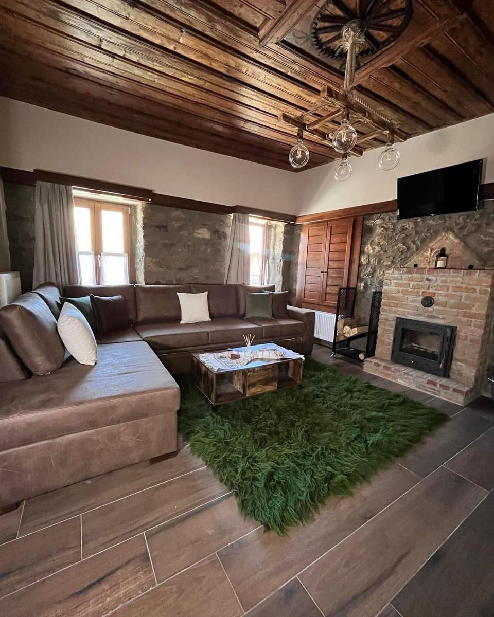 Home 3, living room with a wooden ceiling, a leather corner sofa and a fireplace.