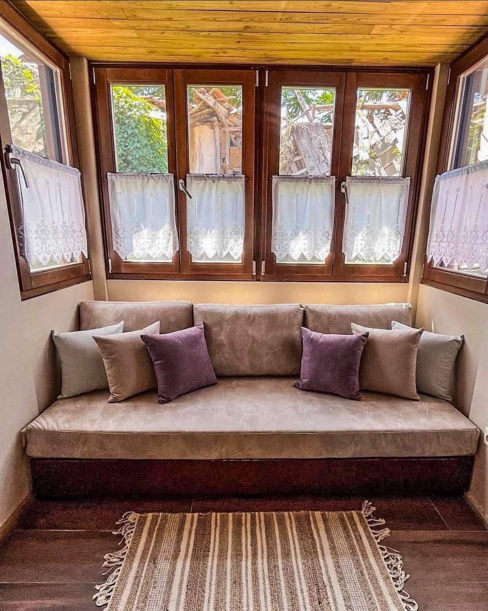 Home 4, cushioned window seat beneath a wooden ceiling and a row of casement windows.